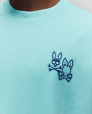 Mens Luke Back Graphic Tee, classic fit aqua jersey knit with a dark blue dual Psycho Bunny skull and crossbones graphic print, one with a floral ear pattern, on the left chest.