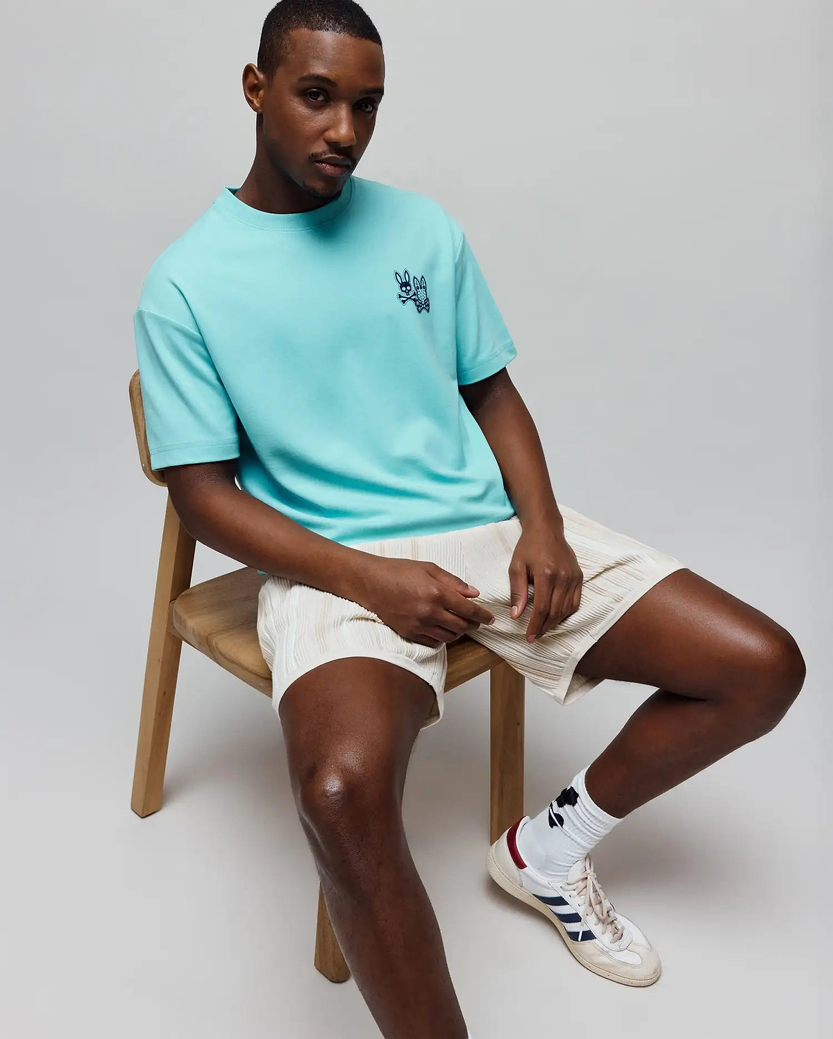Mens Luke Back Graphic Tee, a relaxed fit aqua jersey t-shirt featuring a small, embroidered dark blue Psycho Bunny skull logo on the left chest.