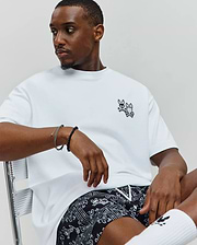 Mens Luke Back Graphic Tee, a crisp white relaxed-fit jersey t-shirt, showcasing a detailed black embroidered Psycho Bunny skull and crossbones logo on the left chest.