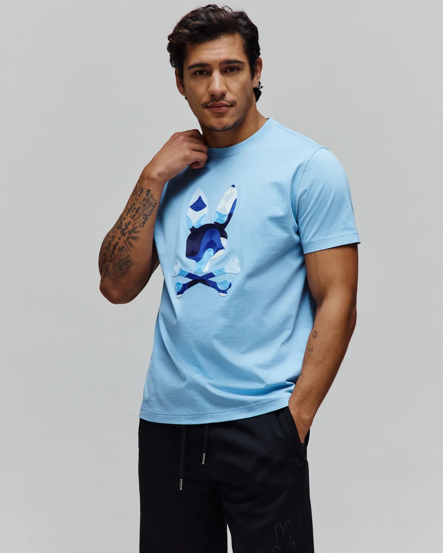 Mens Ara Graphic Tee, light blue classic fit jersey knit t-shirt featuring a large, central chest graphic of the Psycho Bunny skull logo in a faceted blue and white design.