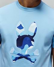 Mens Ara Graphic Tee, a light blue jersey t-shirt with a large, central embroidered Psycho Bunny skull logo in shades of blue and white camouflage, classic fit.