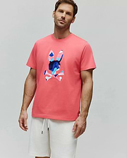 Coral pink Mens Ara Graphic Tee, classic fit jersey, with a large central Psycho Bunny skull logo featuring a vibrant blue, pink, and white camouflage pattern.