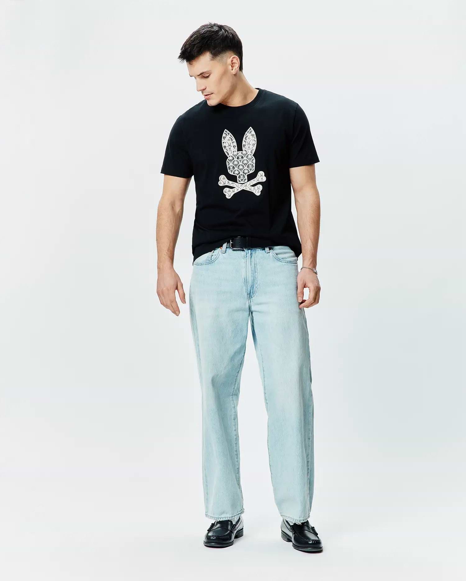 Mens Brad Graphic Tee, black classic fit jersey t-shirt featuring a large white paisley-filled Psycho Bunny skull logo on the chest.