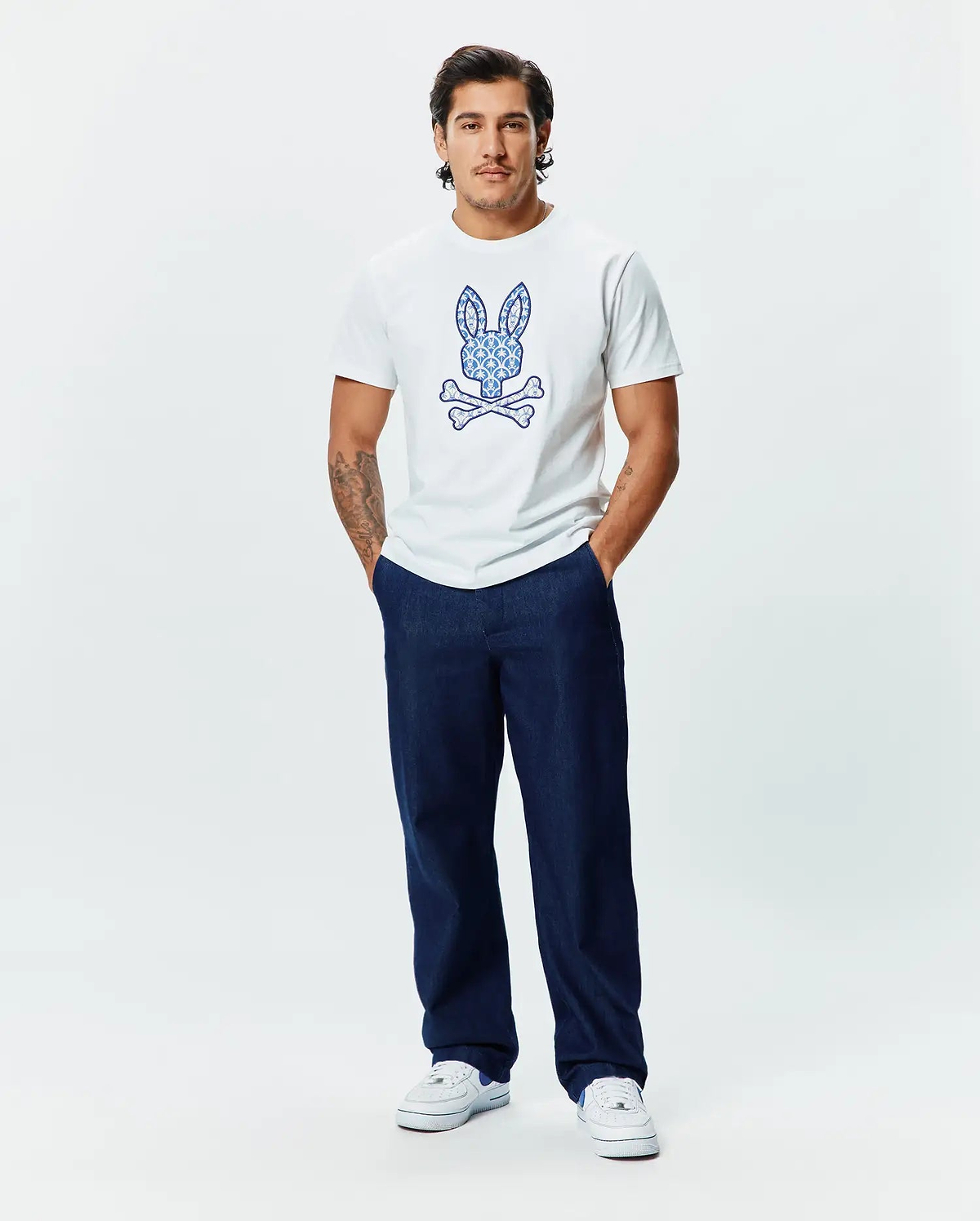 Mens Brad Graphic Tee, white classic fit jersey t-shirt featuring a large, intricately blue patterned Psycho Bunny skull logo centered on the chest.