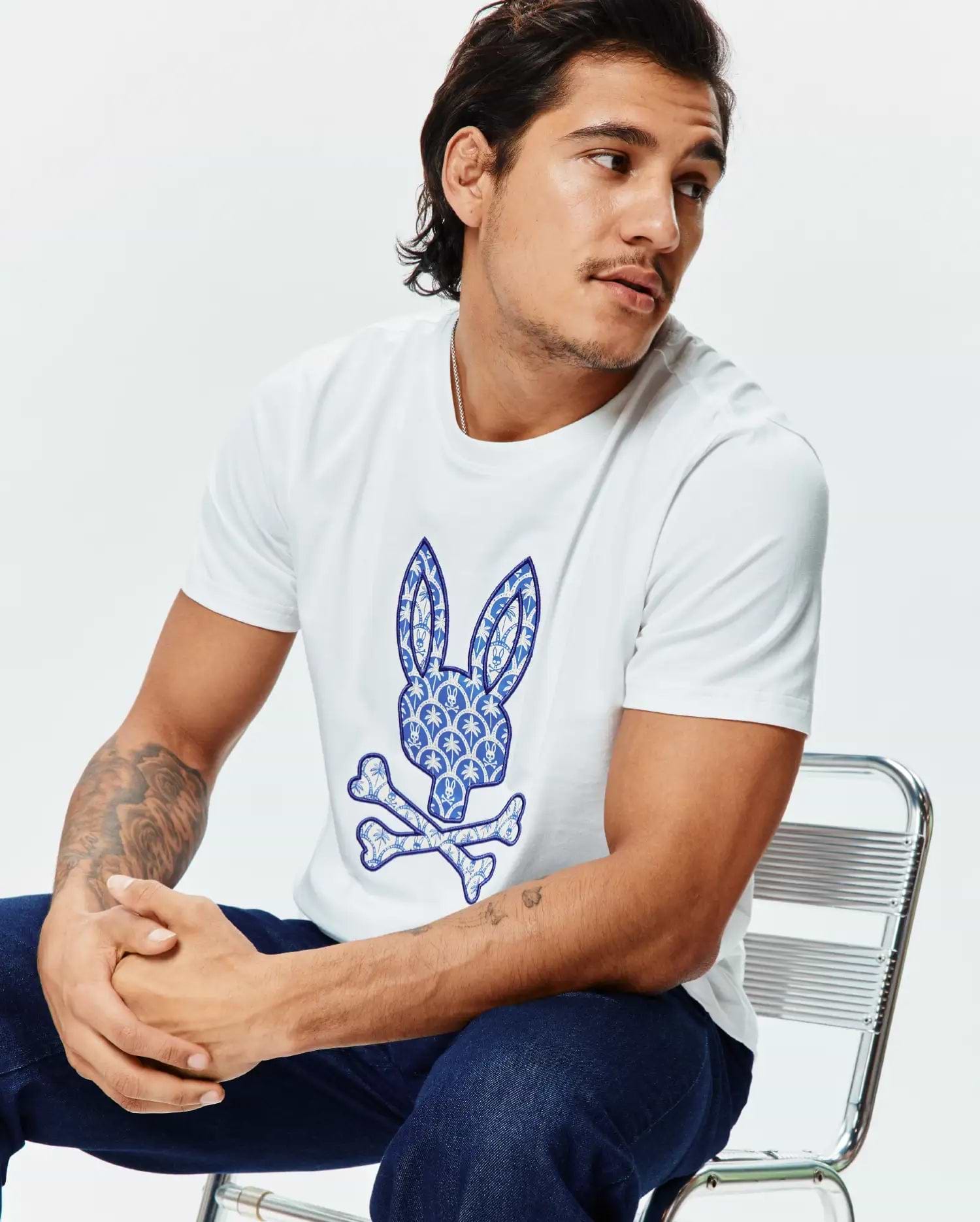 Mens Brad Graphic Tee, a crisp white classic fit jersey t-shirt showcasing a prominent blue and white intricate patterned Psycho Bunny skull logo graphic on the chest.