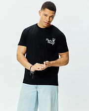 Mens Colin Back Graphic Tee, a black classic fit jersey t-shirt with a prominent white embroidered Psycho Bunny skull and crossbones logo and script text on the left chest.