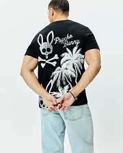 Mens Colin Back Graphic Tee, black jersey knit, classic fit, featuring a large silver Psycho Bunny skull and crossbones, script logo, and palm tree graphic on the back.
