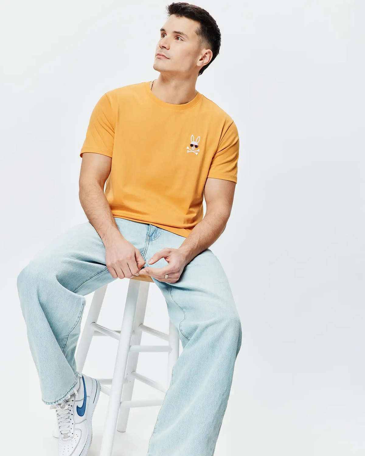 Mens Sunny Chest Graphic Tee in sunny orange, a classic fit jersey t-shirt featuring a small embroidered Psycho Bunny skull with sunglasses and crossbones on the left chest.