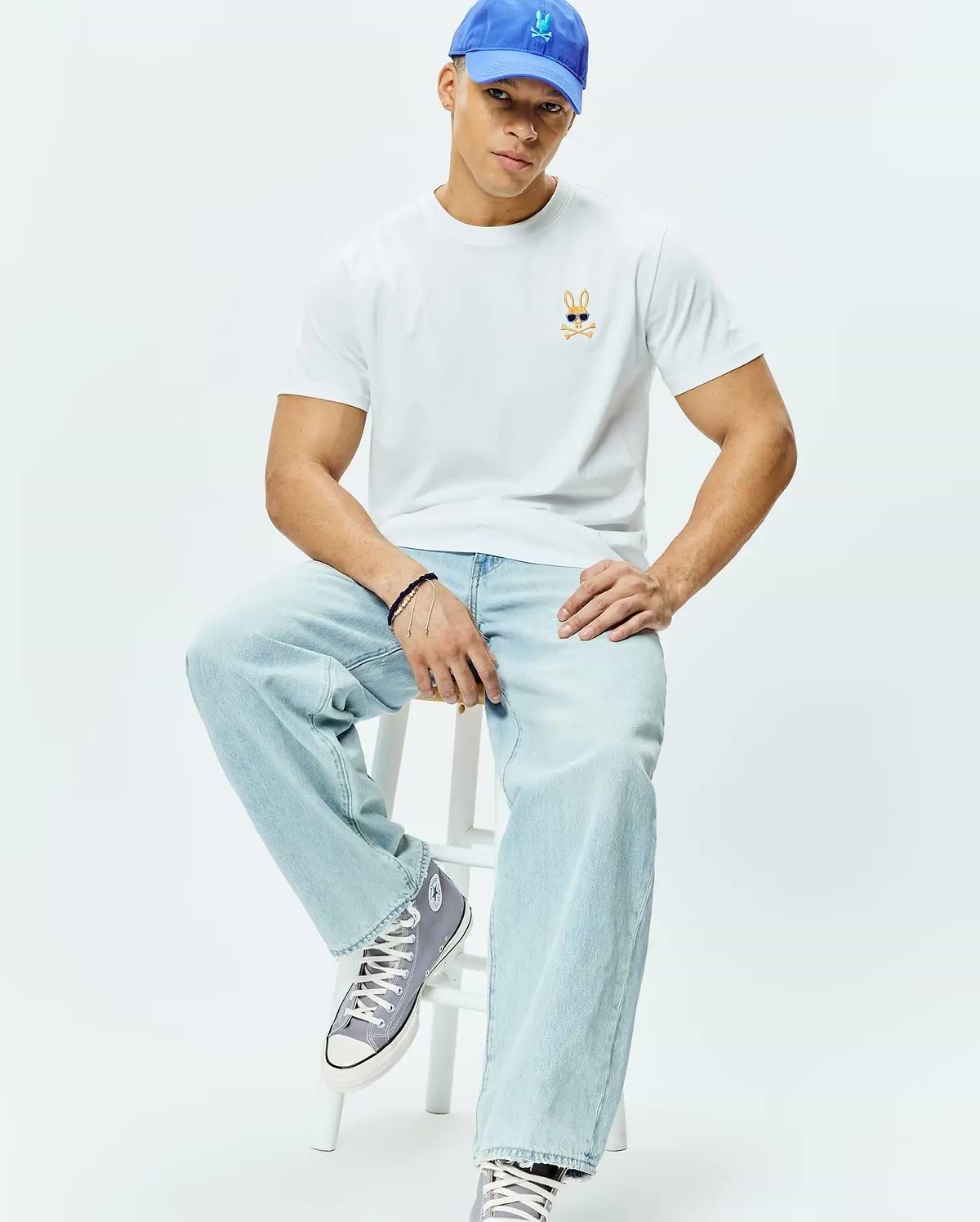 White Mens Sunny Chest Graphic Tee, classic fit, smooth jersey knit, featuring a small embroidered orange and black Psycho Bunny skull with blue sunglasses logo on the left chest.
