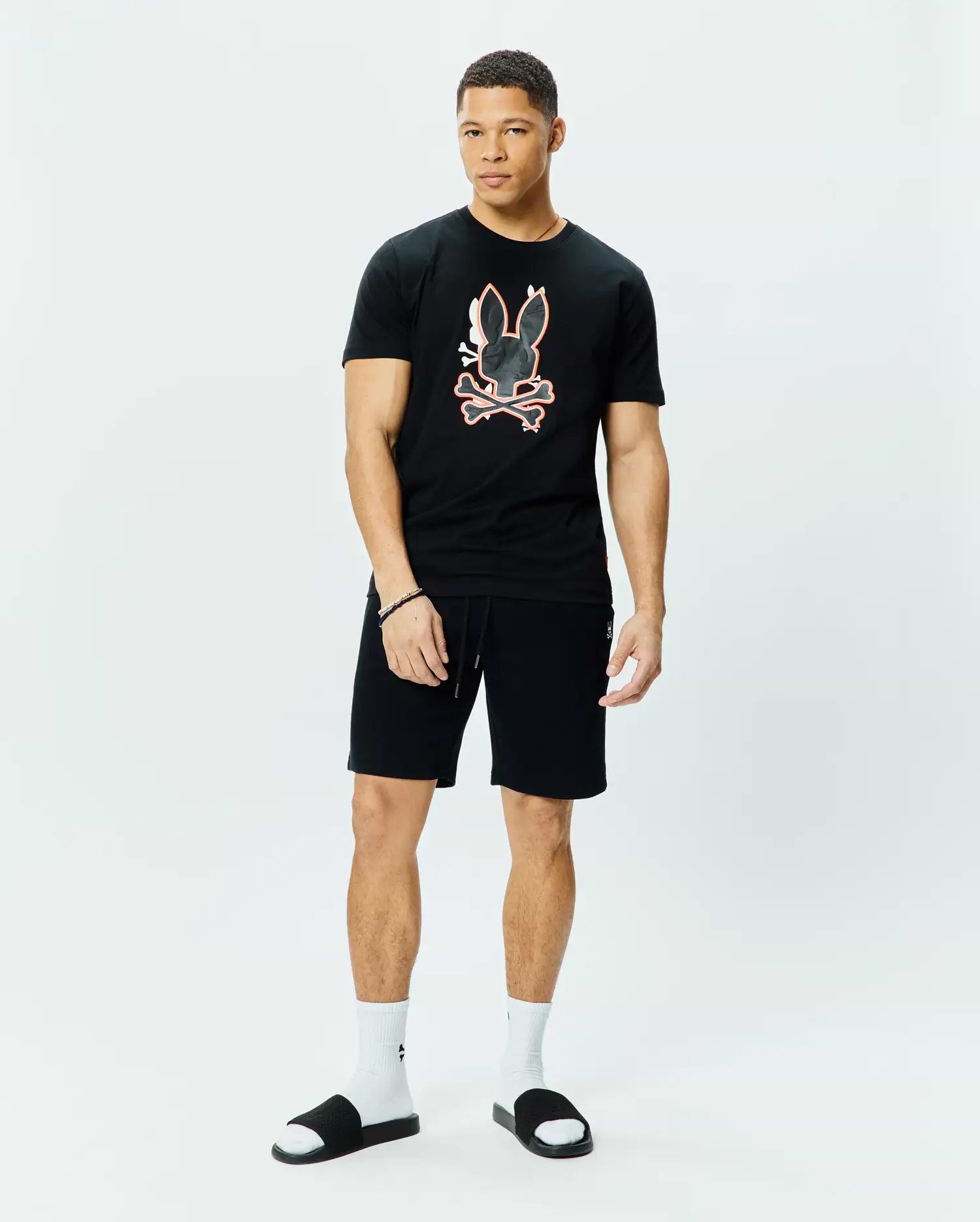 Black Mens Tanner Bunny Graphic Tee, classic fit jersey knit, with a large central orange-outlined bunny skull and crossbones graphic. Black relaxed fit knit shorts with drawstring and small embroidered bunny logo.