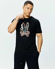 Mens Tanner Bunny Graphic Tee, a black jersey t-shirt with a classic fit, featuring a large central Psycho Bunny skull and crossbones graphic in dark grey camo texture with white and orange outlines.