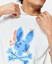 Mens Tanner Bunny Graphic Tee, a white classic fit jersey t-shirt featuring a large central blue camouflage bunny skull logo with light blue outline and crossed bones, accented with orange and pink details. (3)