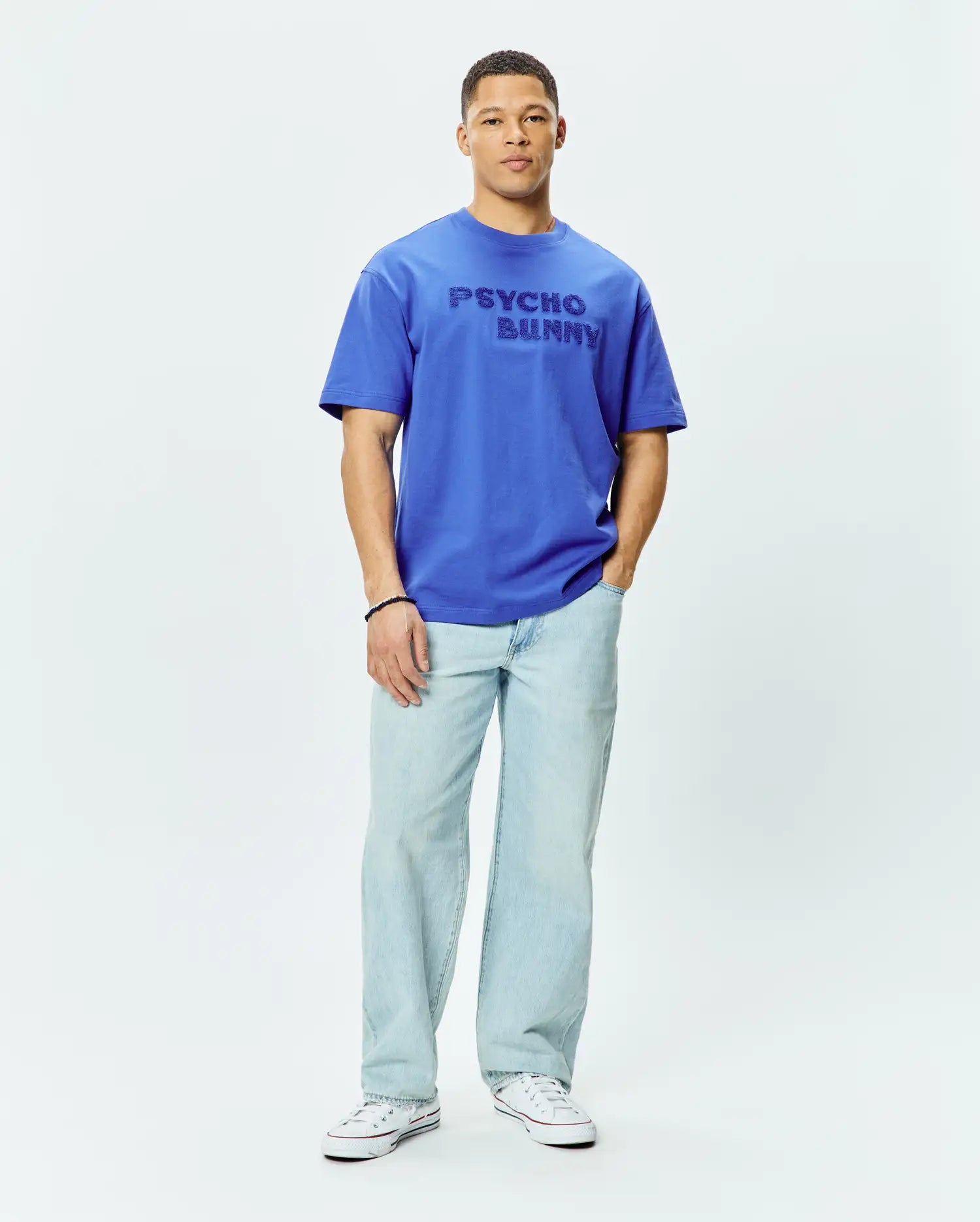 Mens Craig Wordmark Tee, a premium royal blue relaxed fit jersey t-shirt featuring a large tonal embroidered PSYCHO BUNNY wordmark prominently centered on the chest.
