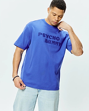 Mens Craig Wordmark Tee, a vibrant royal blue relaxed fit jersey knit t-shirt featuring a prominent, textured tonal Psycho Bunny wordmark across the chest.