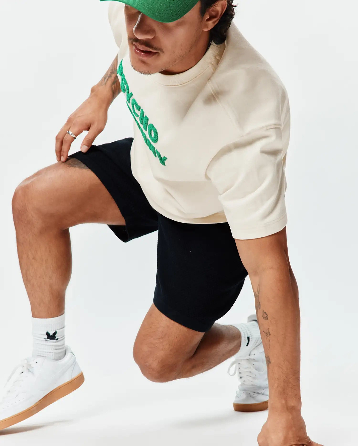 Mens Craig Wordmark Tee, an off-white jersey tee with a bold green PSYCHO chest logo, paired with black relaxed shorts and white socks featuring the iconic bunny skull.