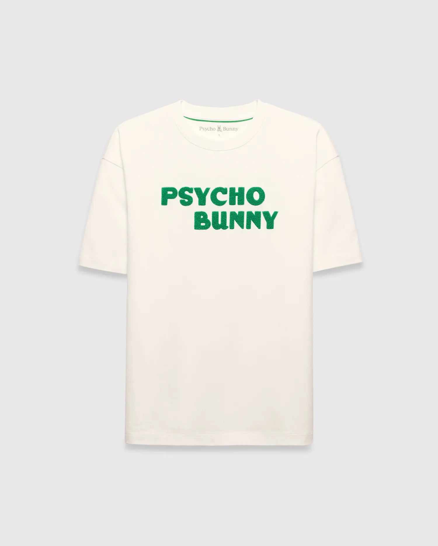 Mens Craig Wordmark Tee, a cream relaxed fit jersey t-shirt featuring a prominent green textured PSYCHO BUNNY wordmark graphic on the chest and a small green logo on the inner neck.