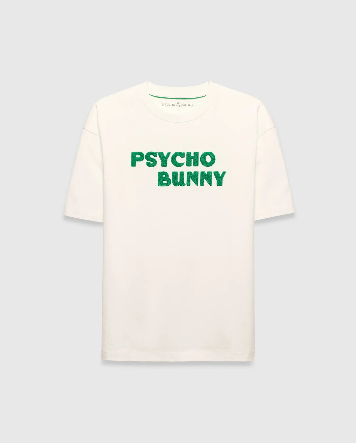 Mens Craig Wordmark Tee, a cream relaxed fit jersey t-shirt featuring a prominent green textured PSYCHO BUNNY wordmark graphic on the chest and a small green logo on the inner neck.
