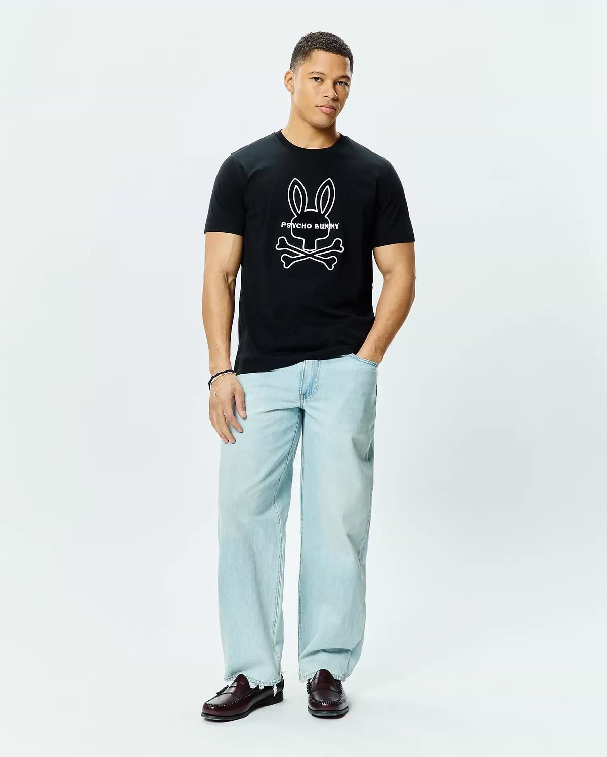 Mens Craig Graphic Tee, a classic fit black cotton jersey t-shirt featuring a large white outline Psycho Bunny skull and crossbones graphic logo centered on the chest.