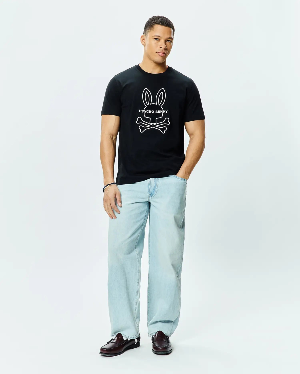 Mens Craig Graphic Tee, a classic fit black cotton jersey t-shirt featuring a large white outline Psycho Bunny skull and crossbones graphic logo centered on the chest.