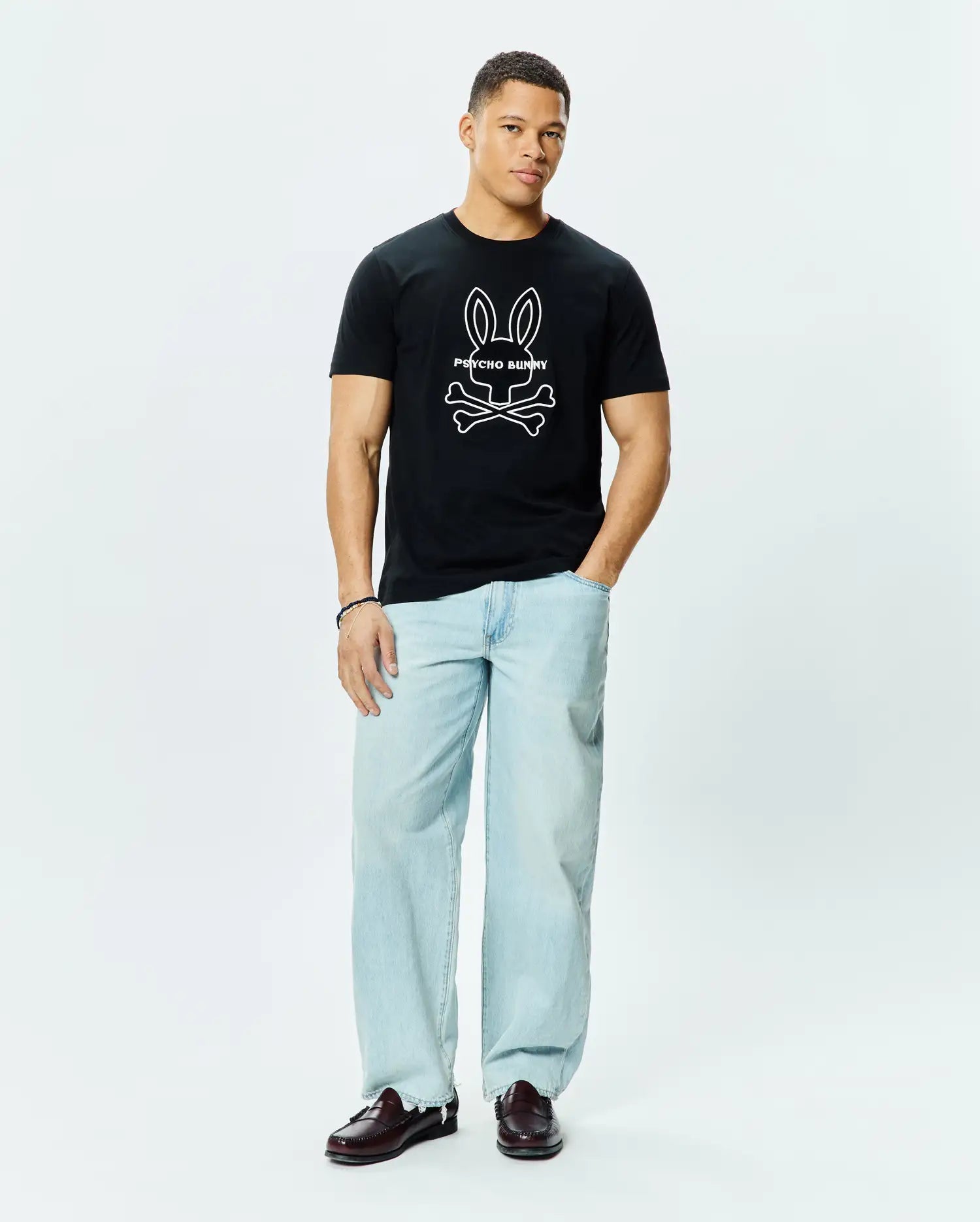 Mens Craig Graphic Tee, a classic fit black cotton jersey t-shirt featuring a large white outline Psycho Bunny skull and crossbones graphic logo centered on the chest.