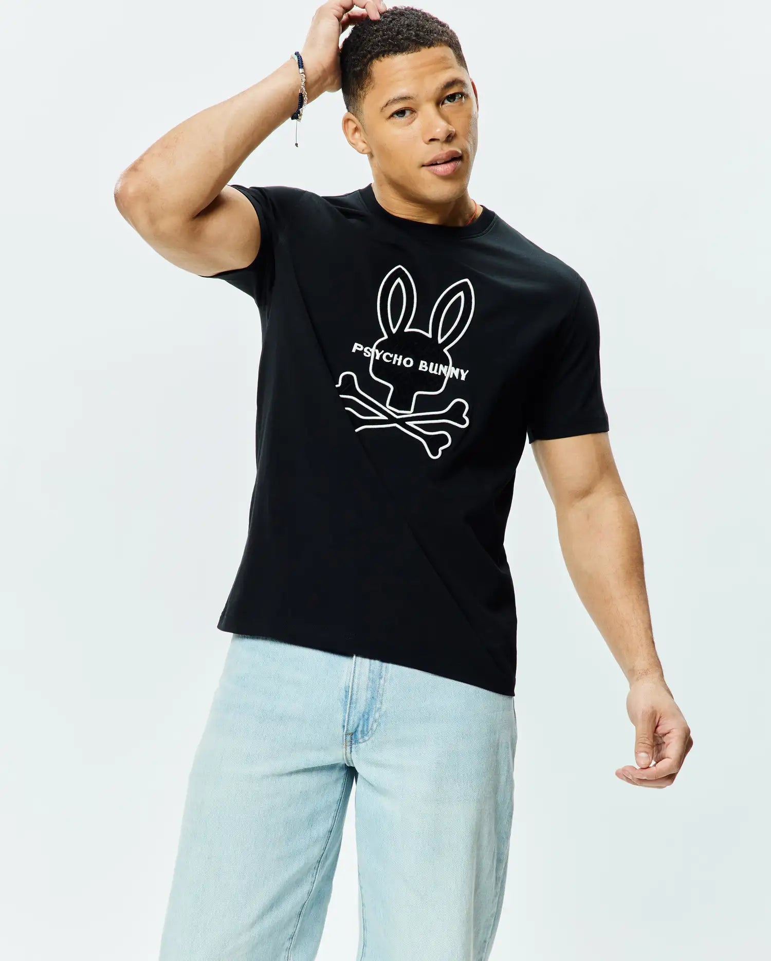 Mens Craig Graphic Tee, black classic fit jersey knit with a large white Psycho Bunny skull and crossbones logo and text graphic prominently displayed on the chest.