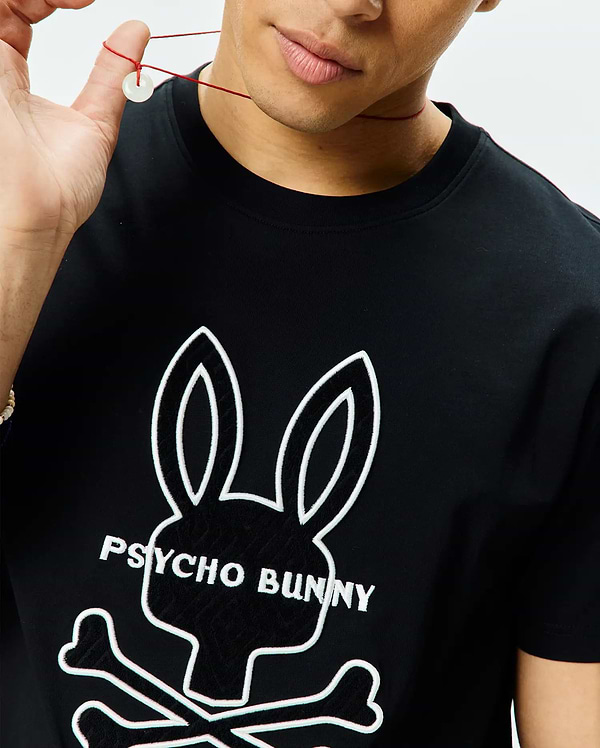 Black Mens Craig Graphic Tee in soft jersey knit, classic fit, featuring a large central white outline of the iconic Psycho Bunny skull logo with black fill and Psycho Bunny text.
