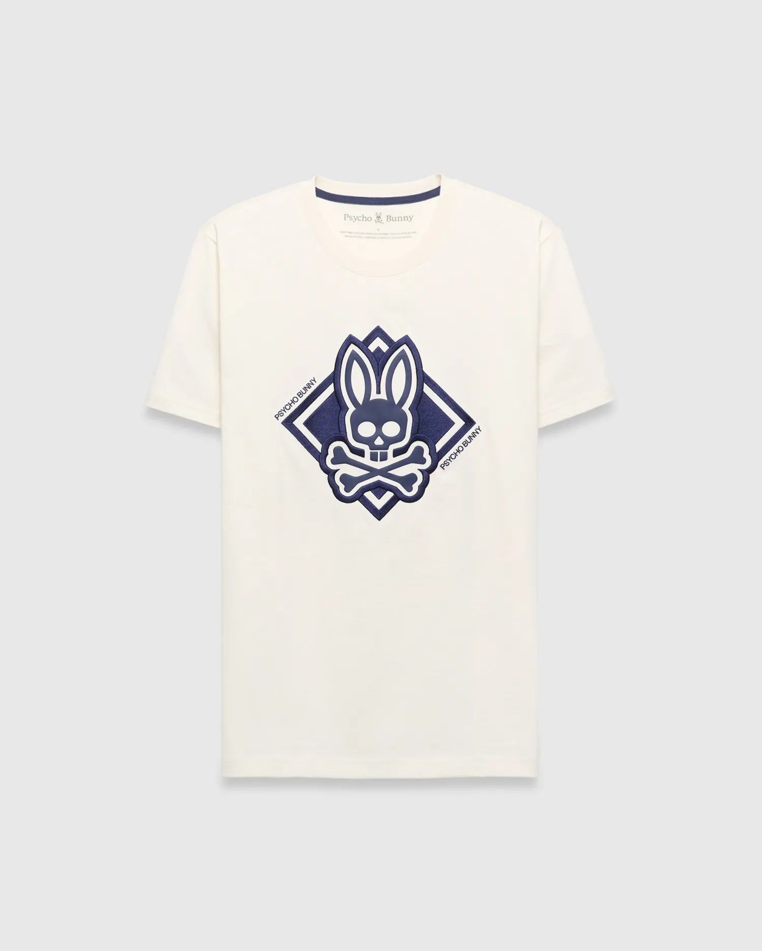 Mens Tobias Graphic Tee, a cream classic fit jersey t-shirt with a large central navy blue Psycho Bunny skull and crossbones logo inside a diamond graphic, featuring Psycho Bunny text.