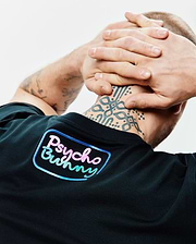 Mens Dayton Graphic Tee in black jersey knit, featuring a large gradient pink, blue, and green Psycho Bunny text logo with a light blue outline on the upper back. (3)