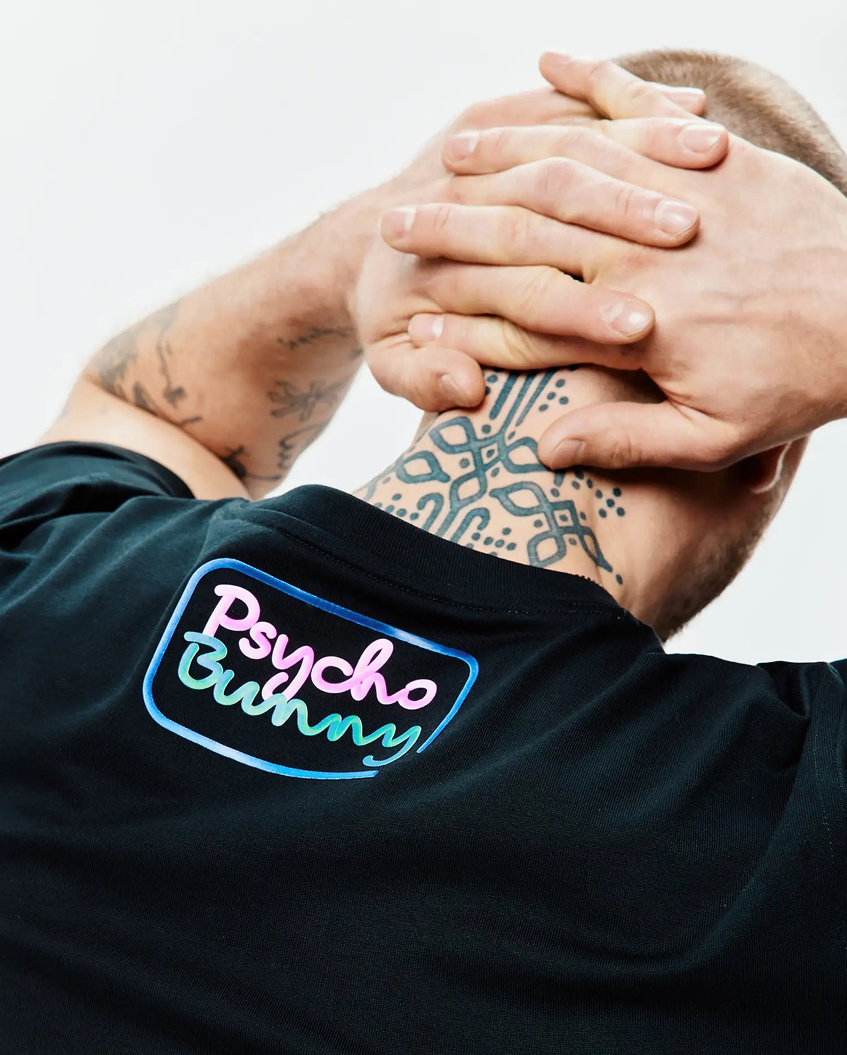 Mens Dayton Graphic Tee in black jersey knit, featuring a large gradient pink, blue, and green Psycho Bunny text logo with a light blue outline on the upper back. (3)