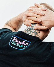 Mens Dayton Graphic Tee in black jersey knit, featuring a large gradient pink, blue, and green Psycho Bunny text logo with a light blue outline on the upper back. (3)