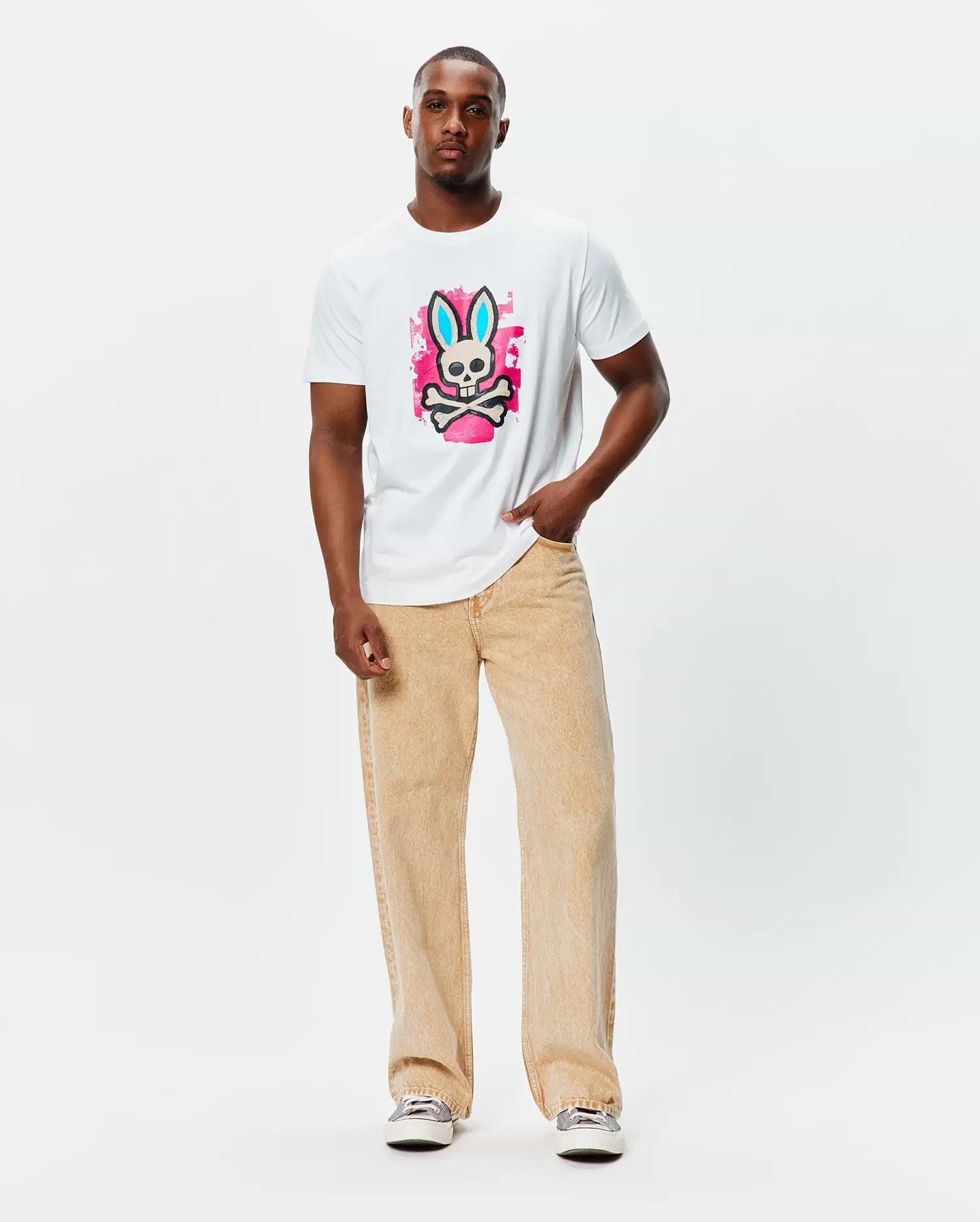 Mens Marcus Bunny Graphic Tee, a classic fit white jersey t-shirt featuring a large central graphic of the Psycho Bunny skull with blue ears on a vibrant pink paint splatter background.