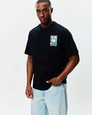 Mens Isaac Relaxed Fit Tee, black jersey with a small chest graphic of the Psycho Bunny skull logo in vibrant pink, blue, green watercolor splatter.