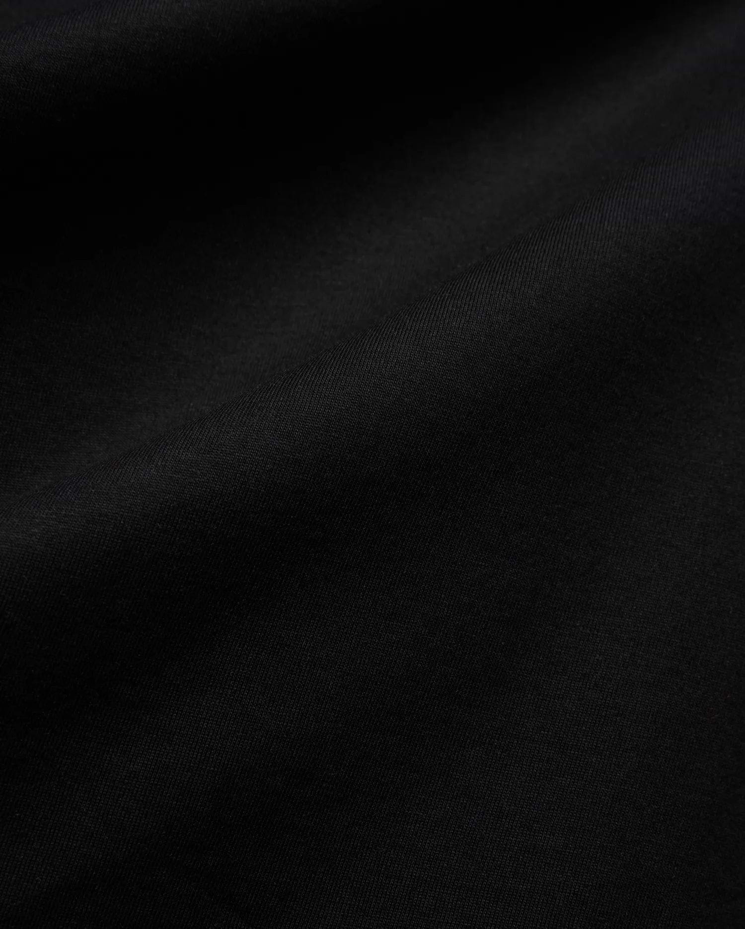 Mens Isaac Relaxed Fit Tee, a premium Psycho Bunny black jersey knit fabric, showcasing its soft, smooth texture with subtle, elegant folds, ideal for refined streetwear.