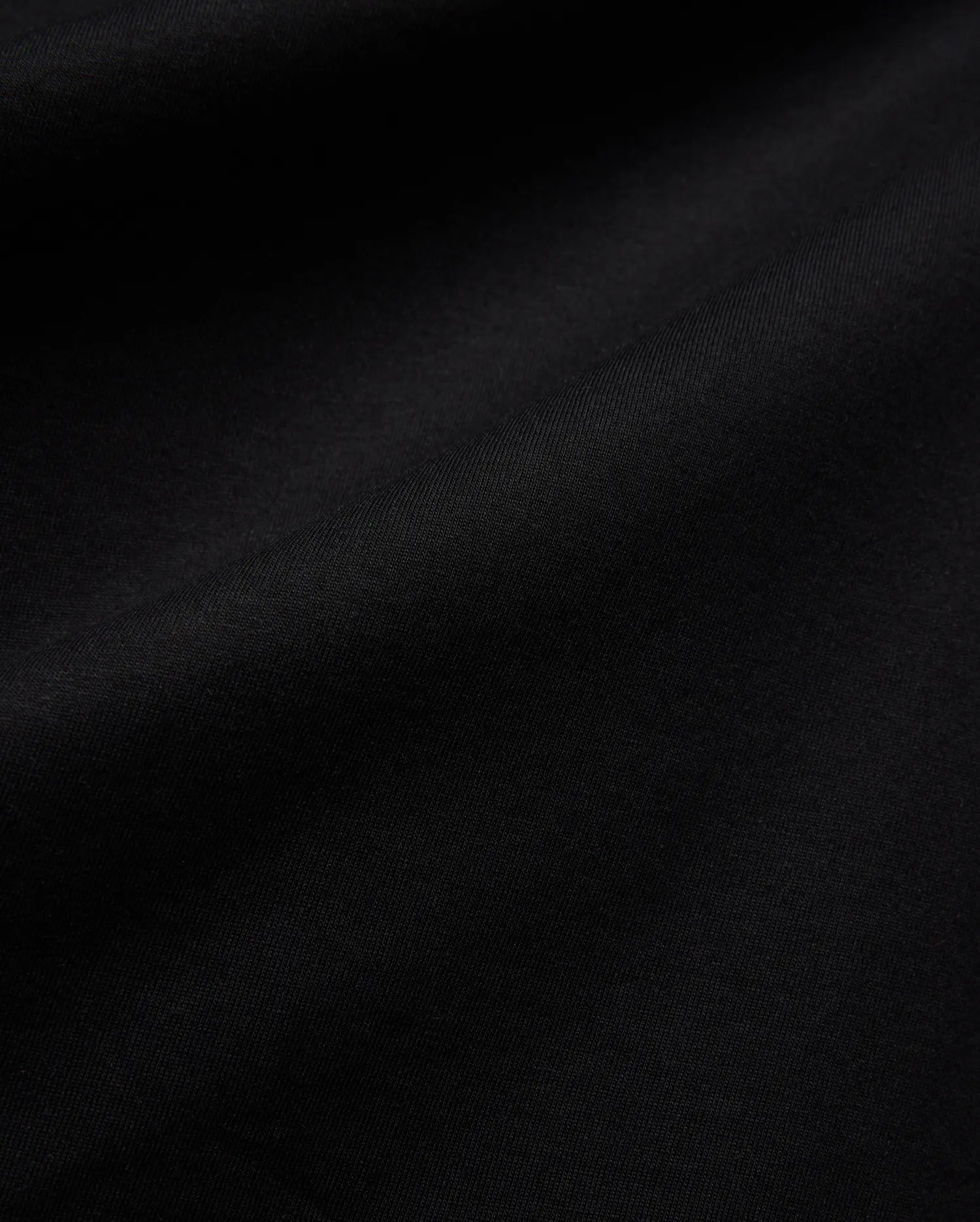 Mens Isaac Relaxed Fit Tee, a premium Psycho Bunny black jersey knit fabric, showcasing its soft, smooth texture with subtle, elegant folds, ideal for refined streetwear.