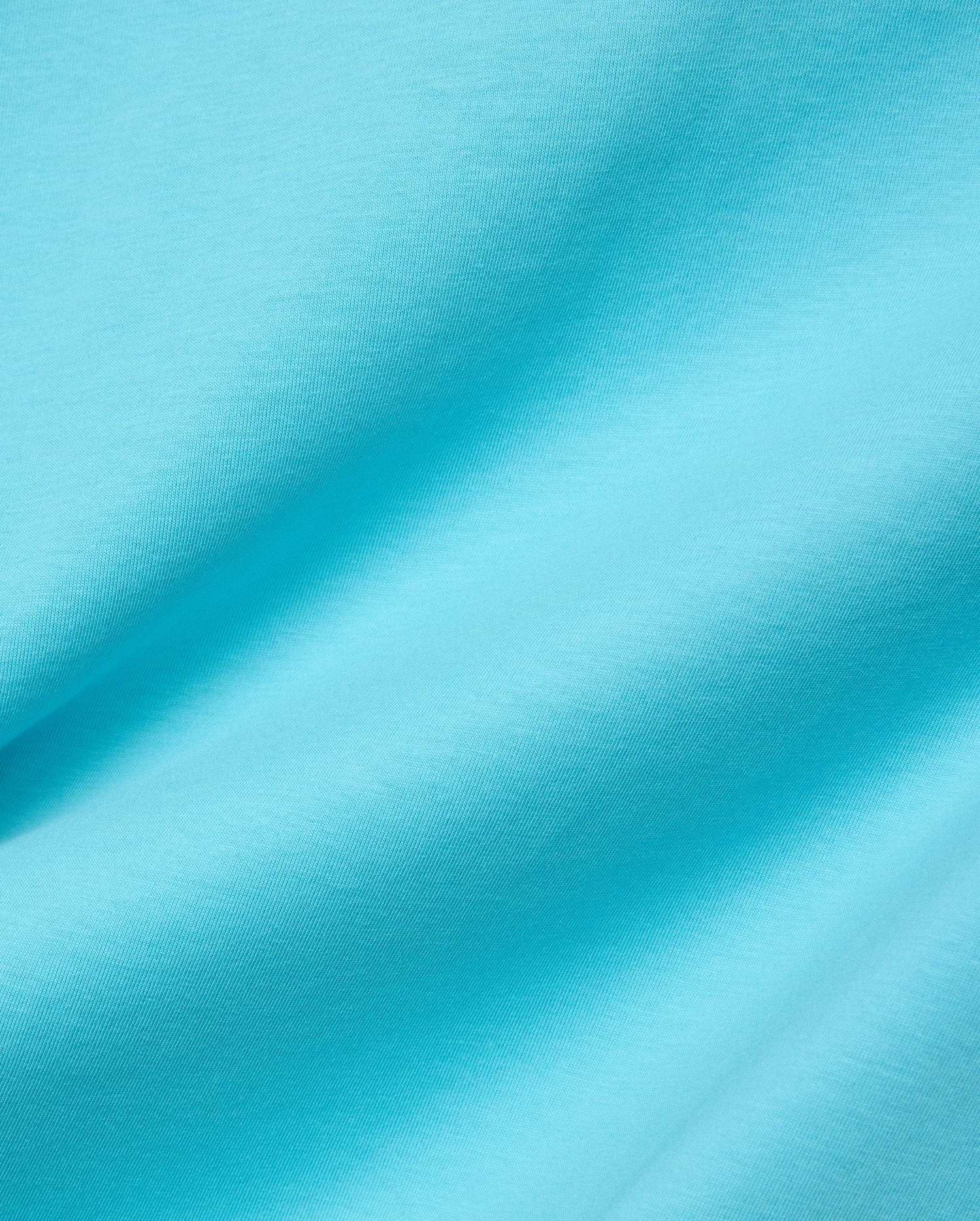 Mens Isaac Relaxed Fit Tee in bright aqua blue, soft jersey knit fabric with visible subtle texture and gentle folds, featuring the iconic small embroidered Psycho Bunny skull logo on the chest.