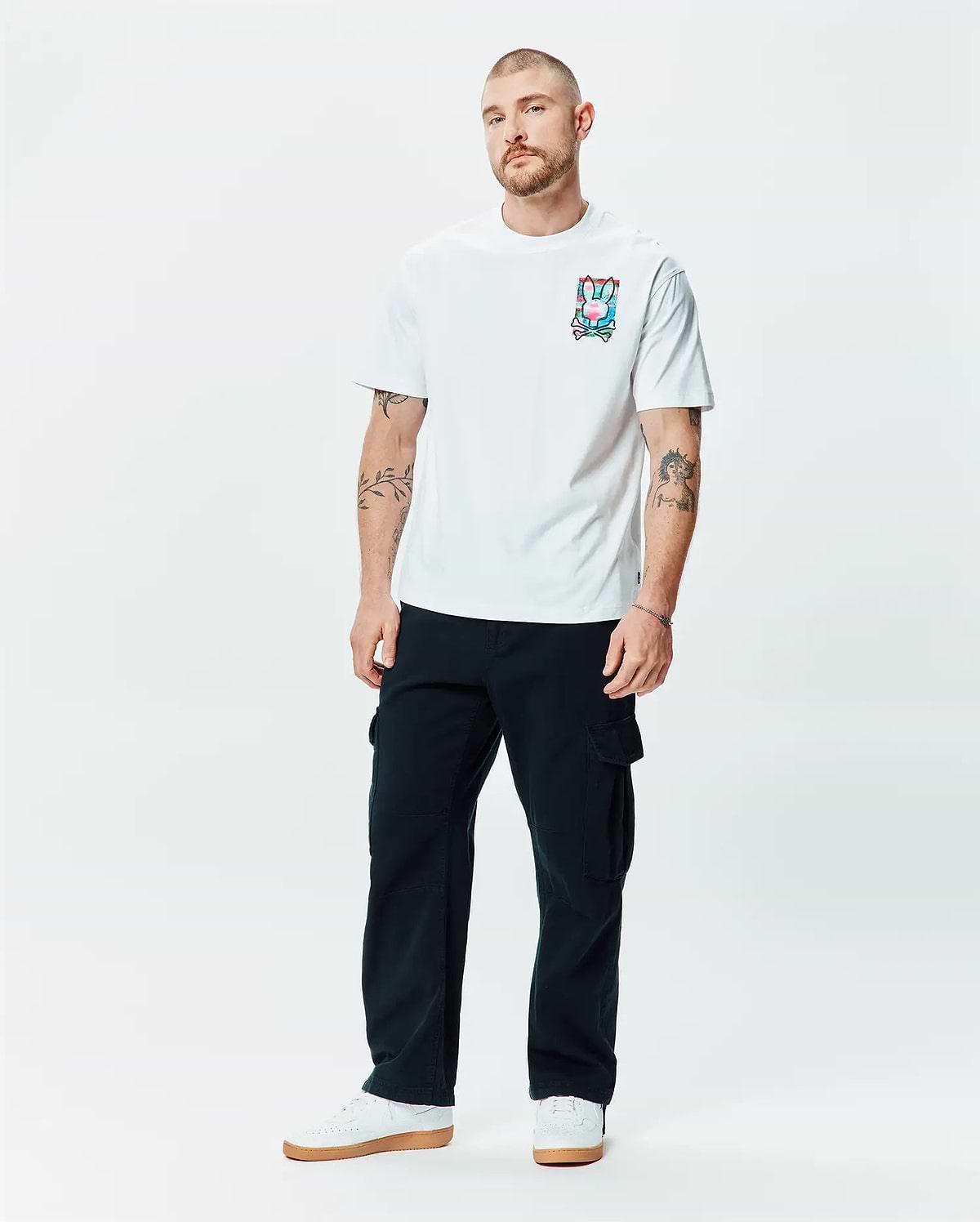 Mens Isaac Relaxed Fit Tee in white soft jersey, featuring a relaxed fit and a vibrant, multi-color Psycho Bunny skull and crossbones graphic print on the left chest.