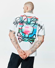 Mens Isaac Relaxed Fit Tee, a white soft jersey t-shirt with a large back graphic of a vibrant, watercolor-style Psycho Bunny skull logo in pink, blue, and green, overlaid with bold black script.
