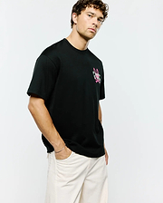 Mens Duncan Relaxed Fit Tee, black jersey knit with a relaxed fit, featuring a prominent pink and white Psycho Bunny skull and crossbones logo on the left chest.