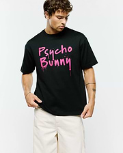 Mens Duncan Wordmark Relaxed Fit Tee, a black jersey t-shirt featuring a large pink graffiti-style Psycho Bunny wordmark with paint drips and splatters on the chest.