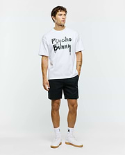 White Mens Duncan Wordmark Relaxed Fit Tee in jersey fabric, featuring a large black and grey graffiti-style Psycho Bunny wordmark with splatter and drip effects on the chest.