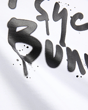 White Mens Duncan Wordmark Relaxed Fit Tee featuring a large, central black graffiti-style Psycho Bunny wordmark print with subtle paint splatters on smooth jersey fabric.