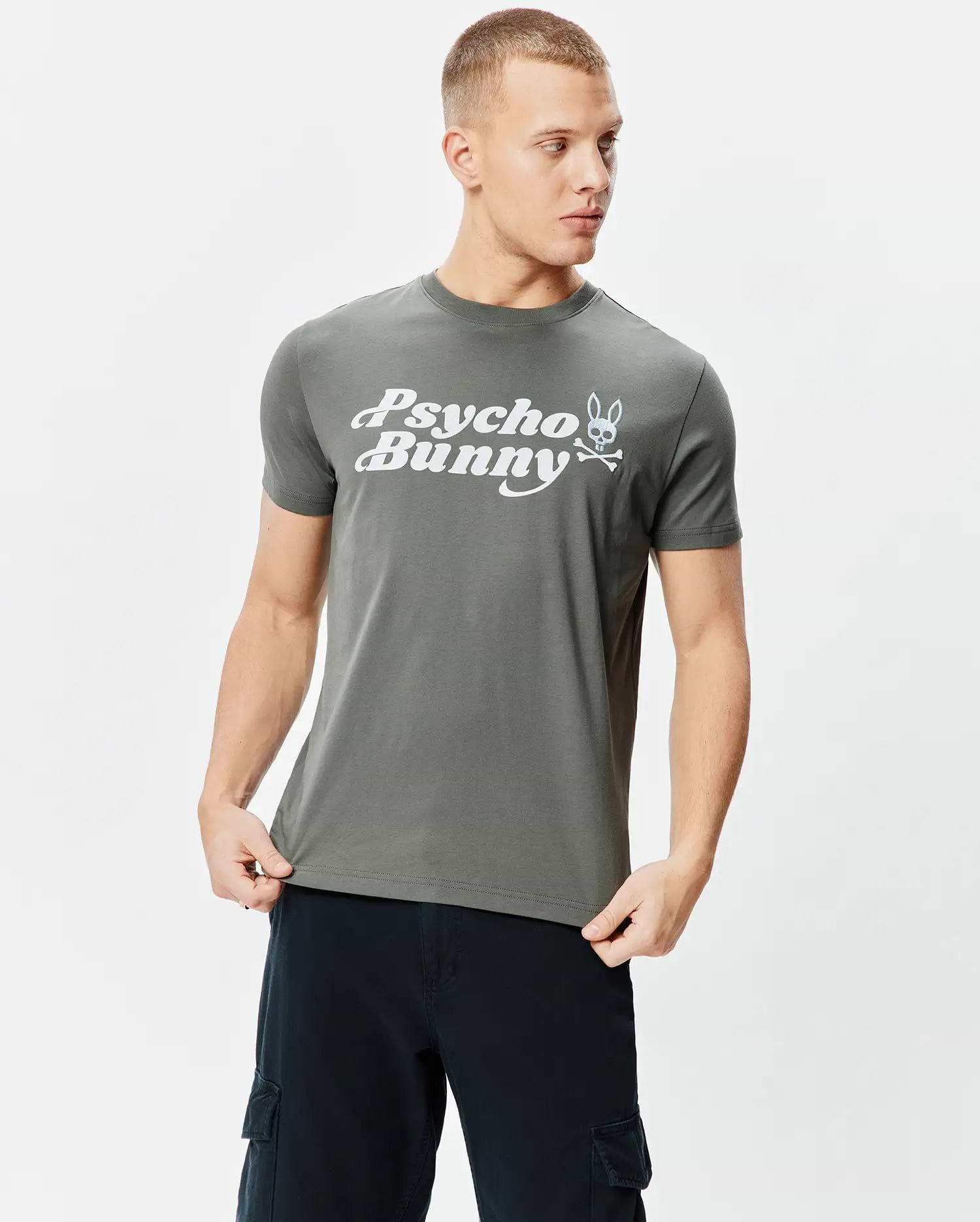 Dark grey classic fit jersey Mens Byron Wordmark Tee with a prominent white Psycho Bunny wordmark and iconic bunny skull logo graphic on the chest.