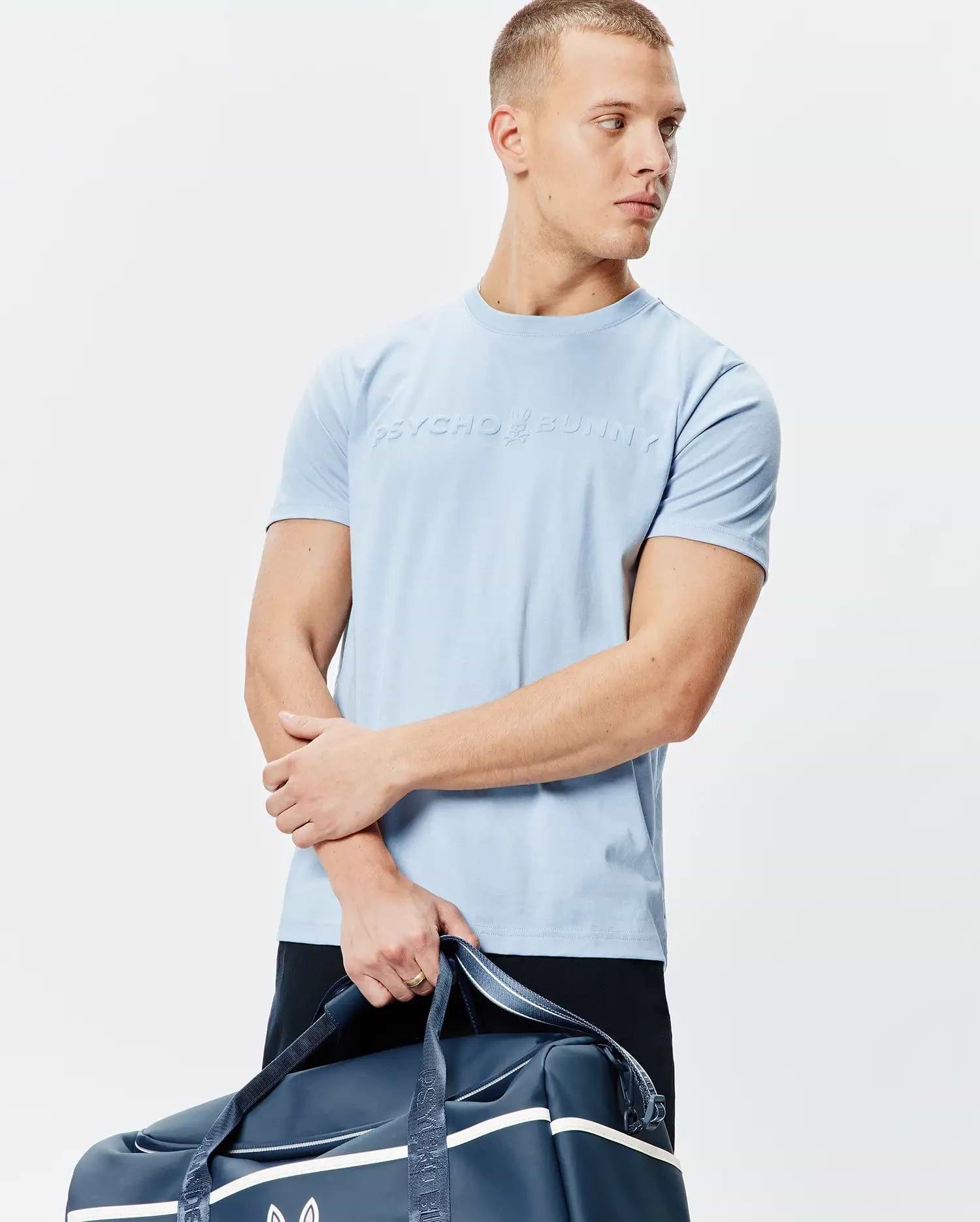 Mens Royce Graphic Tee, sky blue classic fit jersey knit t-shirt featuring a large, raised Psycho Bunny bunny skull logo and text centered on the chest.