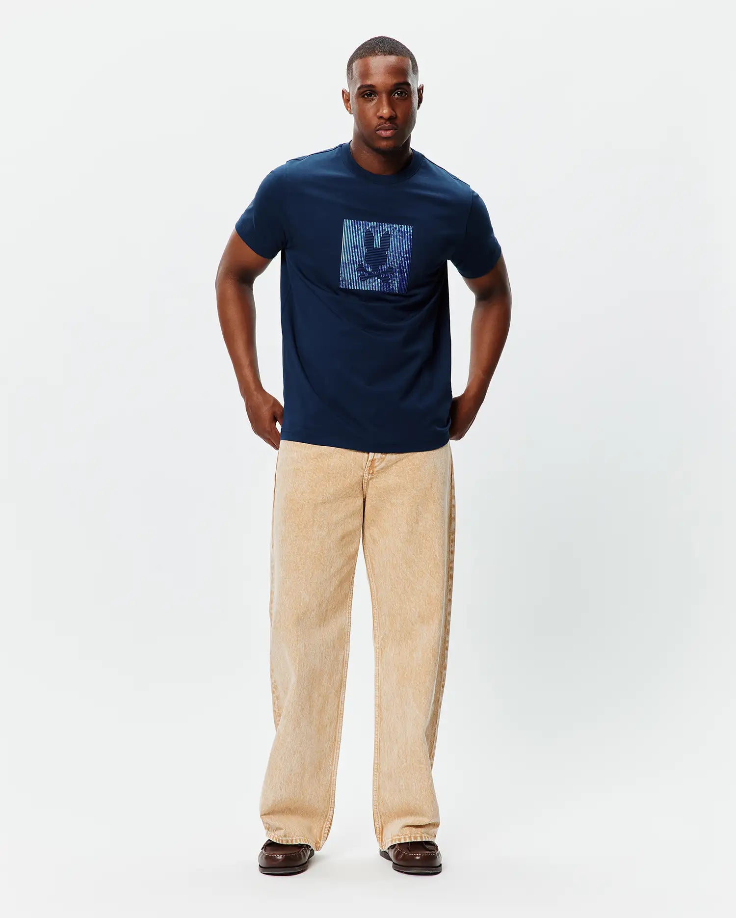 Mens Seamus Graphic Tee, a classic fit navy blue jersey t-shirt featuring a large, centered, iridescent blue and purple pixelated Psycho Bunny skull logo graphic on the chest.