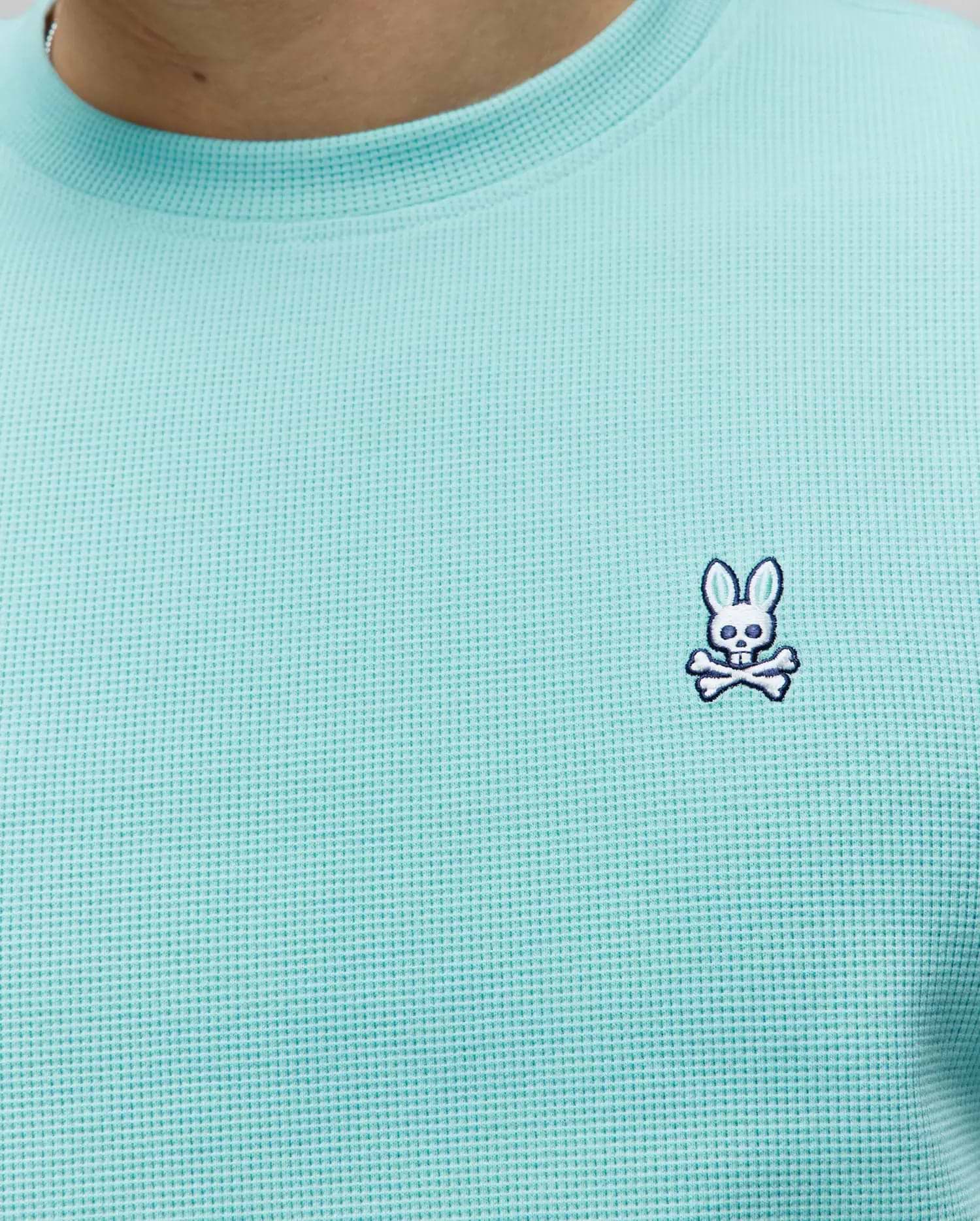 Mens Maxton Waffle Tee in aqua, featuring a classic fit and textured waffle knit fabric, with a small embroidered white, black, and blue Psycho Bunny skull logo on the left chest.