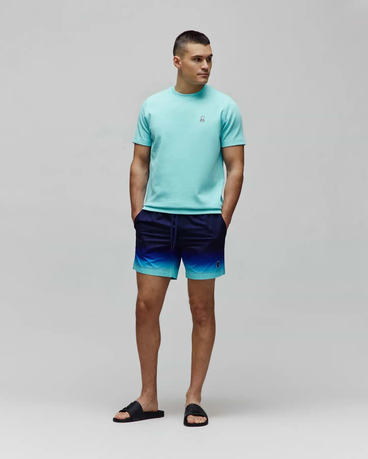 Mens Maxton Waffle Tee in aqua, classic fit, with a small embroidered Psycho Bunny skull logo on the left chest. Ombre swim shorts, navy to aqua gradient, small embroidered Psycho Bunny logo.