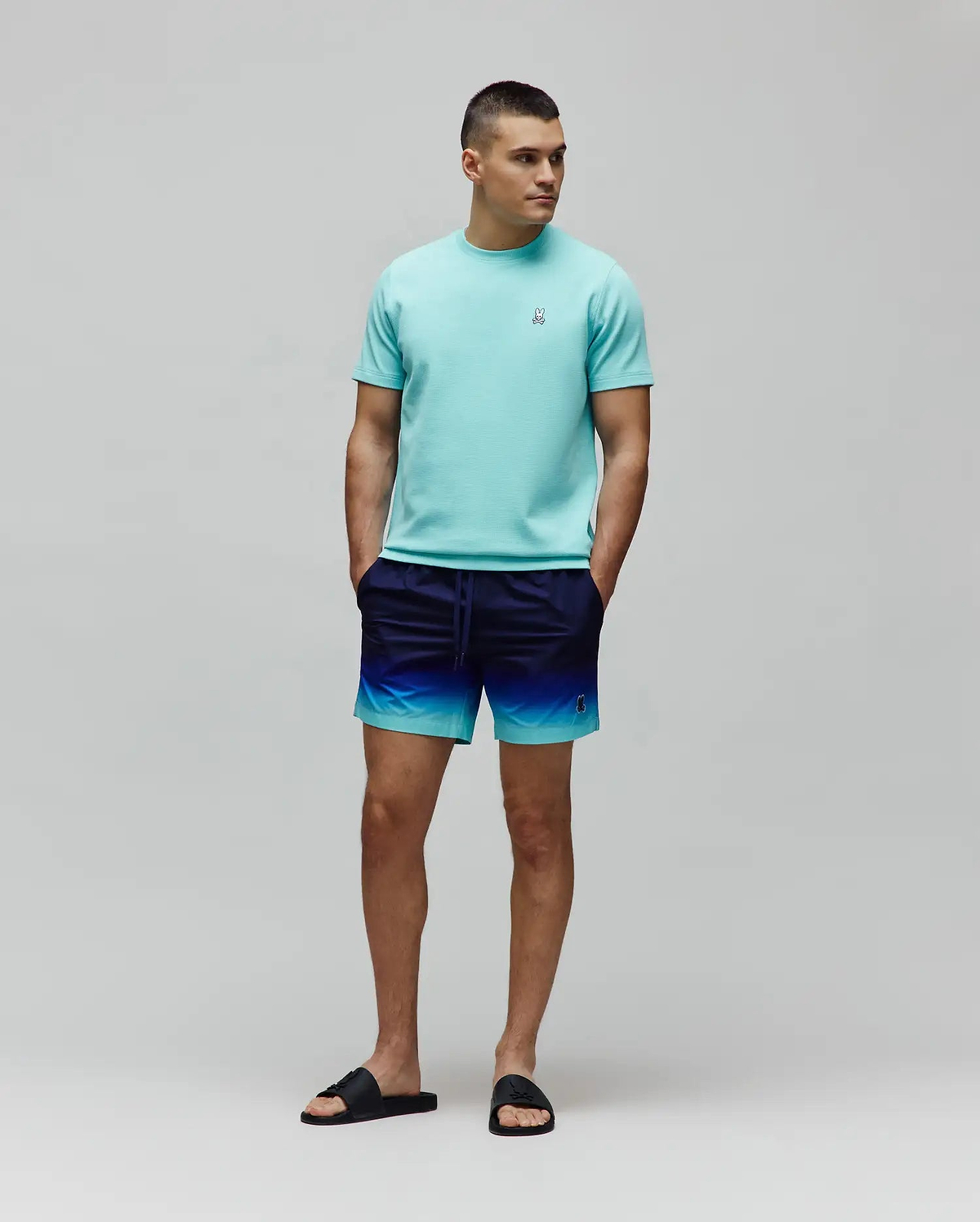 Mens Maxton Waffle Tee in aqua, classic fit, with a small embroidered Psycho Bunny skull logo on the left chest. Ombre swim shorts, navy to aqua gradient, small embroidered Psycho Bunny logo.