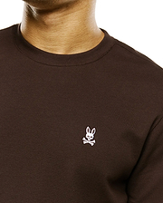 Men's Maxton Waffle Tee, a dark brown classic fit waffle knit long-sleeve t-shirt with a small white embroidered Psycho Bunny skull logo on the left chest. (2)