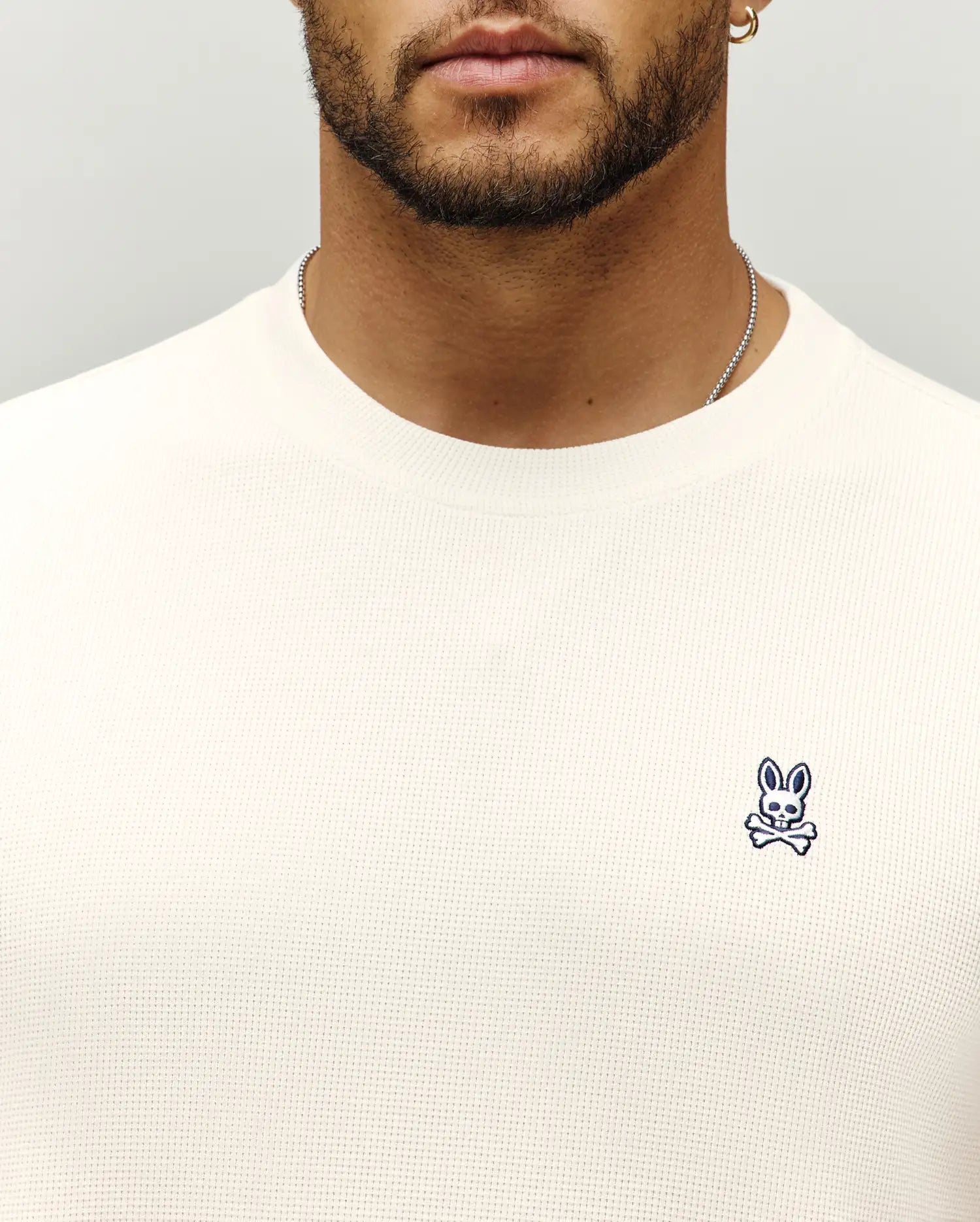 Mens Maxton Waffle Tee in cream, featuring a textured waffle knit fabric and a small, embroidered navy Psycho Bunny skull logo on the left chest.