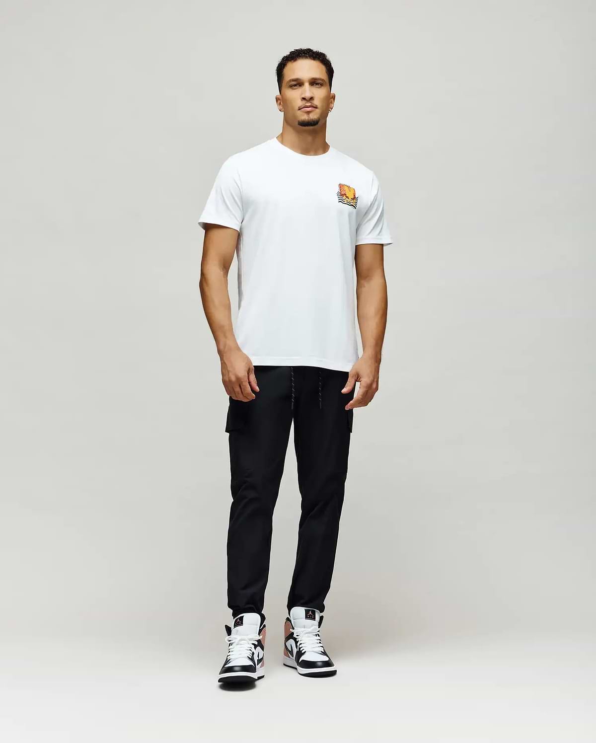 Mens Crazy Bunny Graphic Tee, a classic fit white jersey t-shirt featuring a small, vibrant orange, yellow, and black stylized Psycho Bunny graphic print on the left chest.